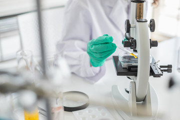 Wall Mural - a scientist working in laboratory with test tube microscope and solutions.