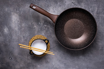 Wok Pan Empty with Wooden Chopsticks on Dark Background. Top View.