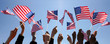 © PEPPERSMINT - Group of People Waving American Flags over blue sky