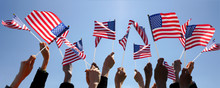 Group Of People Waving American Flags Over Blue Sky