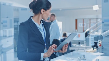 Leinwandbilder - Stylish Female Industrial Robotics Engineer Uses Tablet Computer to Program and Manipulate Robot Arm for Lifting, Moving Objects