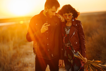 Enjoying time together.  Stylish and loving couple enjoying each other by the sea. The couple is young and in love. The concept of youth, love and lifestyle. Beautiful sunset on a summer day.