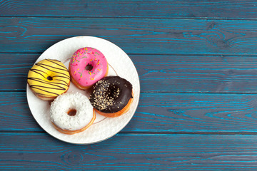 Colorful fresh donuts on dark blue wooden surface