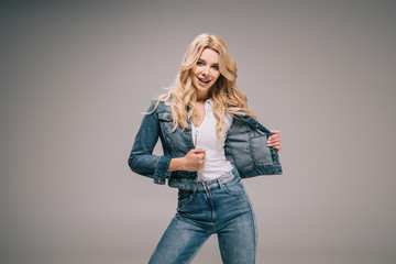 attractive blonde woman in denim jacket and jeans smiling and looking at camera