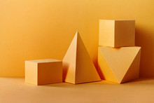 Yellow Geometrical Figures Still Life Composition. Three-dimensional Prism Pyramid Rectangular Cube Objects On Yellow Background. Platonic Solids Figures, Simplicity Concept
