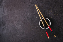 Soy Sauce Bowl And Bamboo Chopsticks Over Black Background. Asian Cuisine Concept