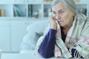 Poster - sad senior woman sitting at table