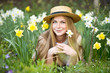 Portrait a beautiful woman in straw hat with  daffodils flowers in the garden. Gardening.