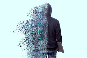 Back view of man in hood, hacker with laptop dispersing and disintegrating into particles of the binary code, concept of technologies and programming