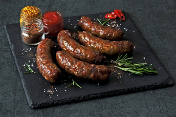 Wall Mural - Appetizing Bavarian or Munich hot sausages with seasonings and sauces on a stone board. Keto menu. Keto diet.