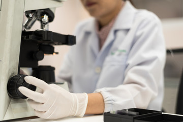 Close up scientist hand adjust the microscopy for scientist diagnosis bacteria from body fluid.Medical tool concept.Selective focus.