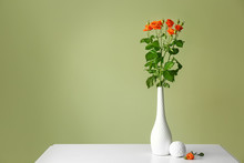 Vase With Beautiful Flowers On Table Against Color Background