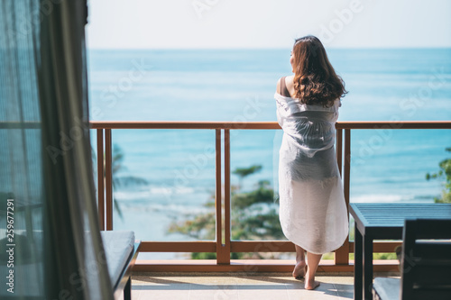 Fotomural A beautiful asian woman standing and enjoy watching the sea view at balcony