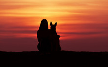 Silhouettes At Sunset, Girl And Dog Against The Backdrop Of An Incredible Sunset, Belgian Shepherd Malinois, Hugging