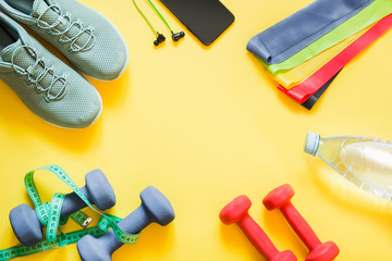 Wall Mural - Sport and fitness equipment, dumbbells, fitness shoes, measuring tape on punchy yellow.