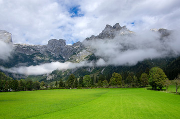 Austrian Verfenveg village Alps mountains autumnal scenery with fog, green meadows and rocks