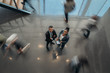 © JonoErasmus - Two business people standing in the lobby of an office looking up smiling at the camera while people are walking past in a blur