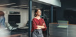 © JonoErasmus - Beautiful young business woman standing in lobby of an office with her arms crossed, looking ahead, with people walking past in a blur