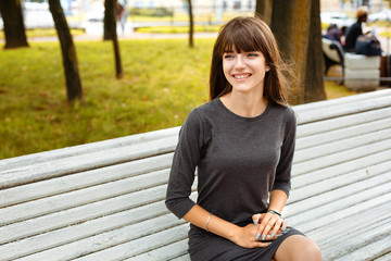 Wall Mural - portrait of a young woman sitting in the Park on a bench