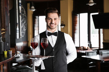 Young Male Waiter With Glasses Of Wine In Restaurant