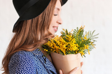 Beautiful young woman with bouquet of mimosa flowers on white background