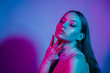 High fashion model in colorful bright neon lights posing at studio. Portrait of beautiful girl with trendy glowing make-up. Art design vivid style.
