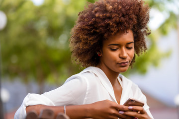 Wall Mural - Outdoor portrait of a Young black African American young woman texting  on mobile phone