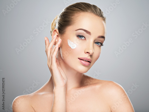 Fotomural woman gets cream in the face. Skin care concept.