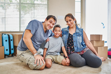 Wall Mural - portrait of happy hispanic family sitting on carpet after moving into new home