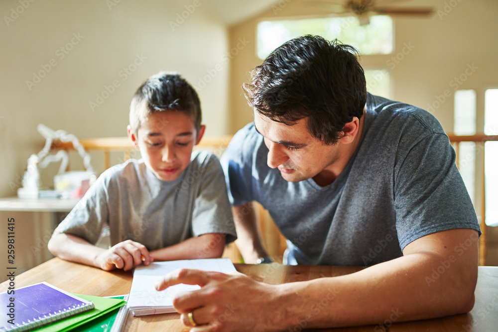 father helping son with homework on table at home Stock Photo | Adobe Stock