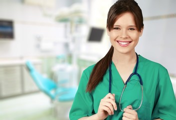 Wall Mural - Attractive young female doctor with blurred hospital interior on background