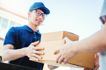 Wall Mural - Delivery concept Asian Man hand accepting a delivery boxes from professional deliveryman at home