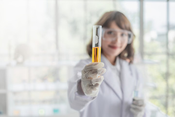 Wall Mural - a young asian woman scientist holding a test tube in a laboratory.