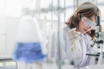 Wall Mural - a young asian woman scientist working in laboratory with test tube microscope and solutions.