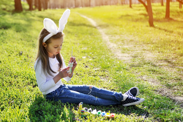 Cute little girl paints Easter`s symbol. Easter concept.