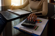 © NIKCOA - Businesswoman or accountant hand using calculator to calculate about budget and writing note on notebook, work on laptop computer with data graph paper at office. e business, e commerce concept.