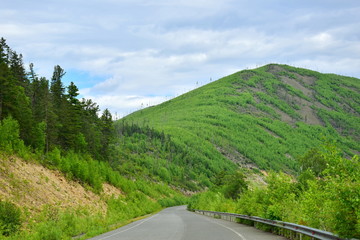 Summer adventure trips. The road between the hills and rocky slopes. Landscape of Sikhote-Alin mountains. Far East, Khabarovsk territory.