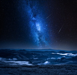 Wall Mural - Milky way with falling stars and foggy valley in Italy