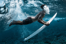 Surfer Performs Dive (the Duck Dive) With His Surfboard Under The Wave And Exhales Air Into The Water.