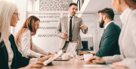 Handsome CEO in formal wear having meeting with his employees in boardroom. Create the kind of climate in your organization where personal growth is expected, recognized and rewarded.