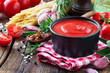 Tomato sauce or ketchup in a black bowl with cooking ingredients at the background