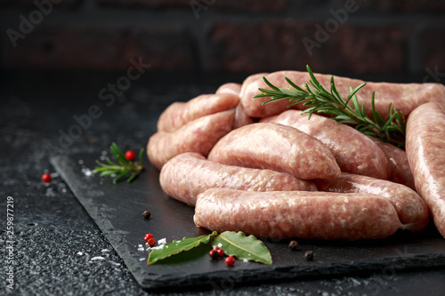 Fotografía Freshly made raw butchers sausages in skins with herbs on stone board