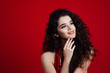 Brunette girl with long curly hair . Beautiful model with curly hairstyle on red background