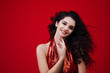 Brunette girl with long curly hair . Beautiful model with curly hairstyle on red background