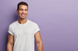 © wayhome.studio  - Indoor shot of handsome muscular guy with positive expression, wears casual mock up white t shirt for your promotion, stands against purple background, free space aside. People and emotions.