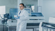 © Gorodenkoff - Male Research Scientist Walks Through Laboratory with Tray of Test Tubes Filled with Samples. In the Background  Working Laboratory with Innovative Equipment.