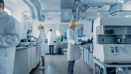Wall Mural - team of research scientists working on computer, with medical equipment, analyzing blood and genetic