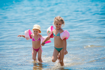 little girls with swimming armbands playing in shallow water