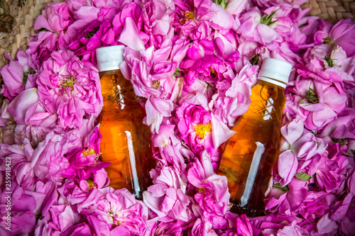 rose water bottles inside a basket of rose petals Tableau sur Toile