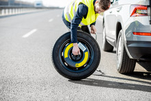Man Changing Wheel Standing With Spare Wheel Near The Broken Car On The Roadside